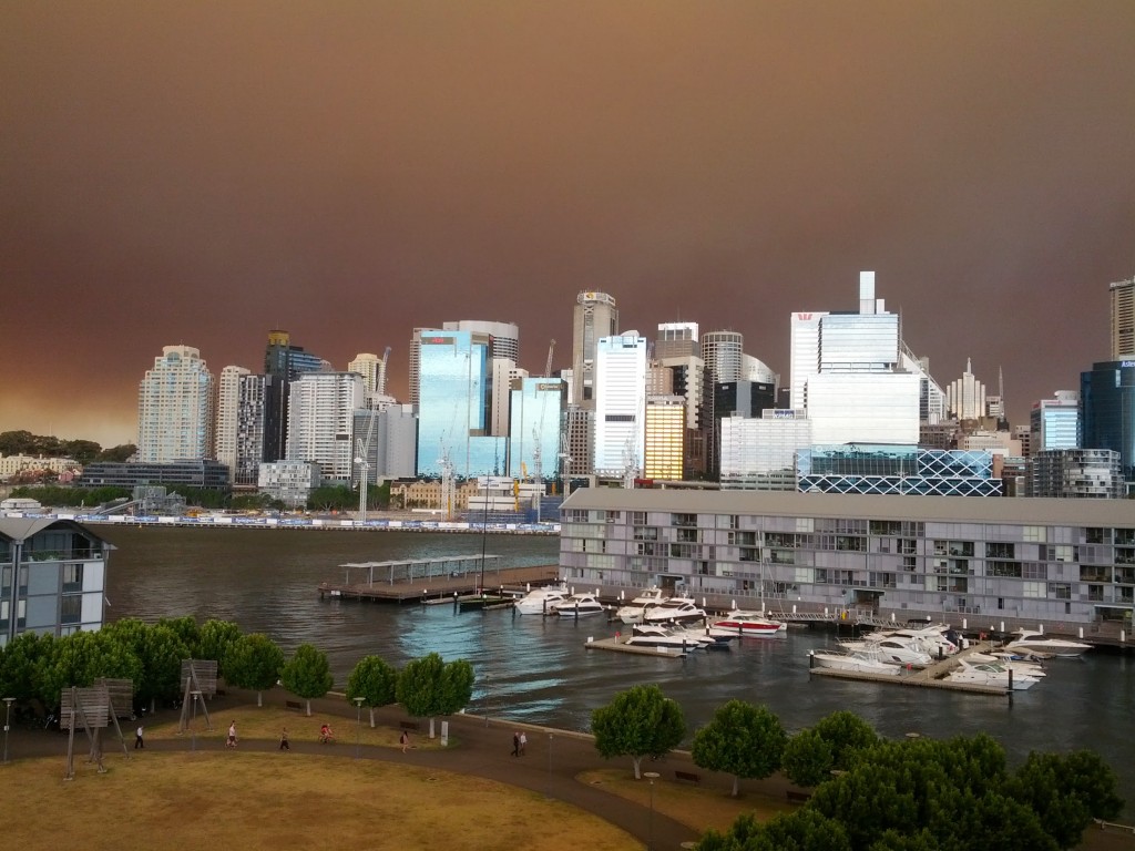 Bu fotoğrafı Sidney'de nerdeyse 1 haftadır süren ve Sidneylilerin olağan karşıladığı çalı yangınları sırasında çektim. Yangın dumanı nedeniyle gökyüzü kül ve dumanla kaplanıyor ve tabiri caizse her şey kırmızımsı tonlara dönüyor. Güneşe baktığınızda koyu turuncu bir leke olarak görüyorsunuz. Foto, çalıştığım katın balkonundan çekildi.